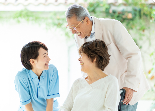 屋外で高齢の家族と一緒に楽しく話している介護士